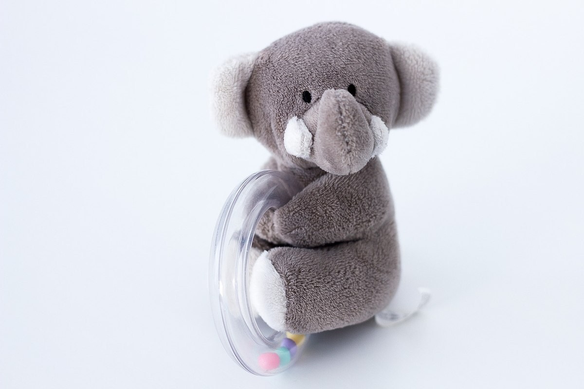 Petit éléphant peluche assis avec un disque transparent et des perles colorées Petit éléphant peluche assis avec un disque transparent et des perles colorées