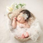 Bébé endormi dans un panier décoré de tulle, fleurs et plumes