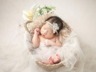 Bébé endormi dans un panier décoré de tulle, fleurs et plumes