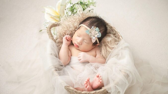 Bébé endormi dans un panier décoré de tulle, fleurs et plumes