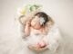 Bébé endormi dans un panier décoré de tulle, fleurs et plumes