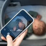 Main tenant smartphone montrant photo d'enfant endormi dans lit d'enfant