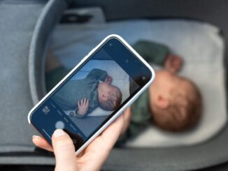 Main tenant smartphone montrant photo d'enfant endormi dans lit d'enfant