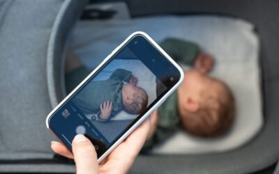 Main tenant smartphone montrant photo d'enfant endormi dans lit d'enfant