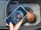 Main tenant smartphone montrant photo d'enfant endormi dans lit d'enfant