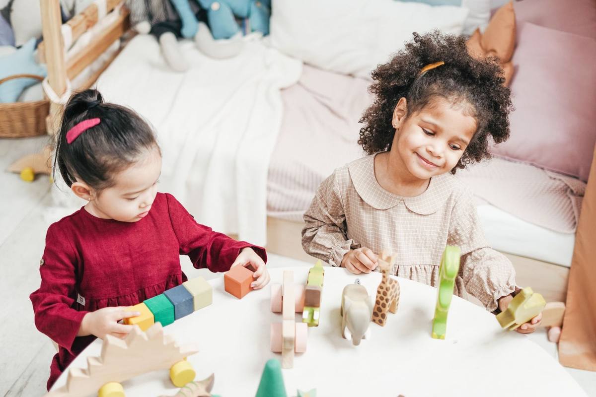 Enfants manipulant des blocs en bois sur une table dans une pièce Enfants manipulant des blocs en bois sur une table dans une pièce