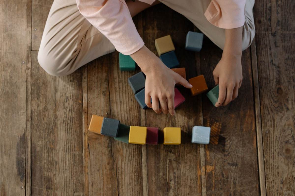 Personne jouant avec des blocs de construction colorés sur le sol Personne jouant avec des blocs de construction colorés sur le sol
