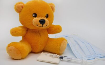 Un ours en peluche jaune à côté d'une seringue et d'un masque