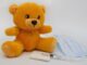 Un ours en peluche jaune à côté d'une seringue et d'un masque
